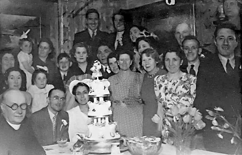 A group of people posing in front of a wedding cake.